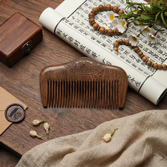 Peigne de poche en bois de santal aux dents fines et motif floral sculpté, posé sur un bureau en bois avec parchemin calligraphié et perles