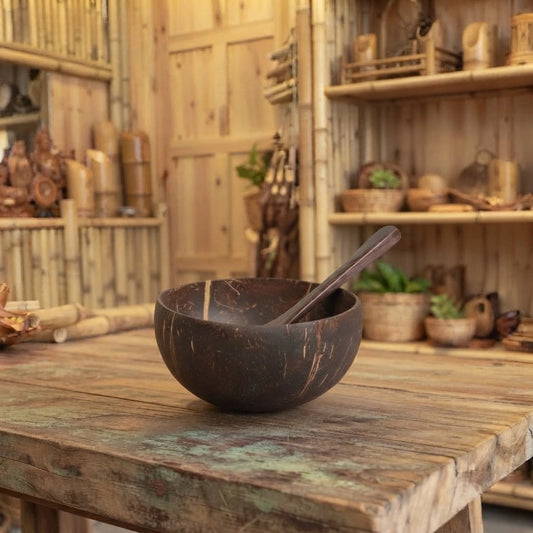 Petit bol en noix de coco avec sa cuillère en bois, posé sur une table en bois brut dans une boutique en bambou