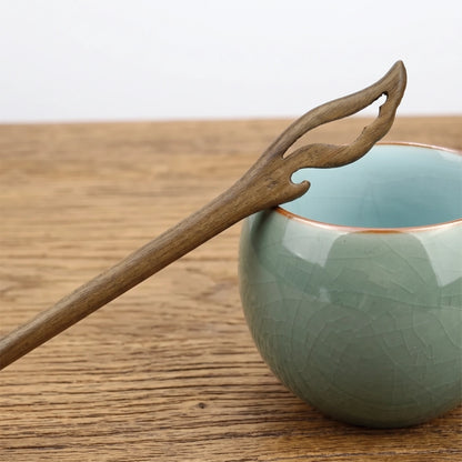Pic à cheveux en bois de santal vert, tête sculptée en double feuille ajourée, posé sur une tasse en céramique