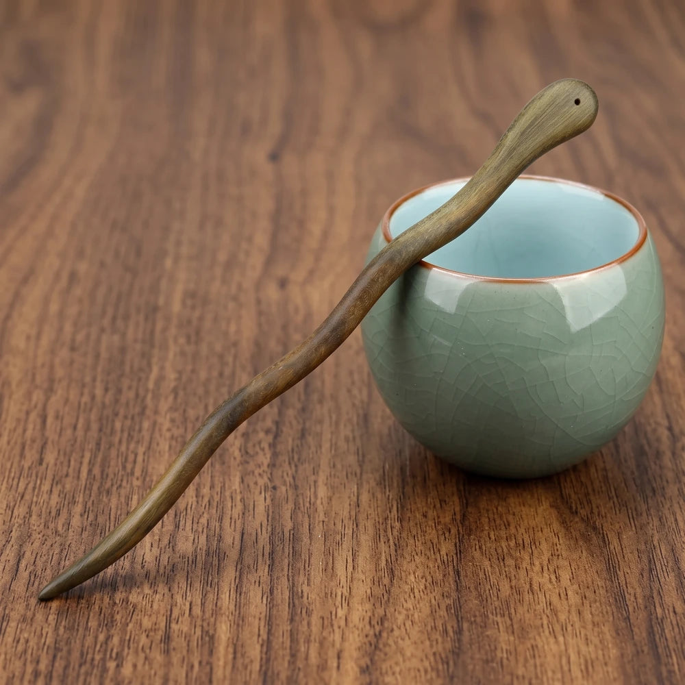 Pic à cheveux en bois de santal vert à tige sinueuse et tête percée, posé sur une tasse en céramique