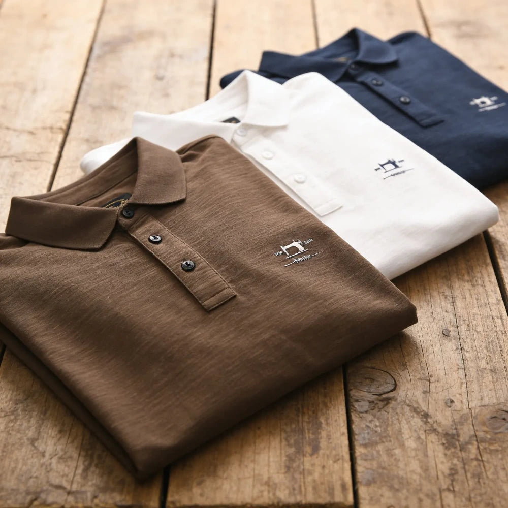 Polos homme en coton et fibre de bambou pliés sur une table en bois, trois coloris café blanc et bleu marine