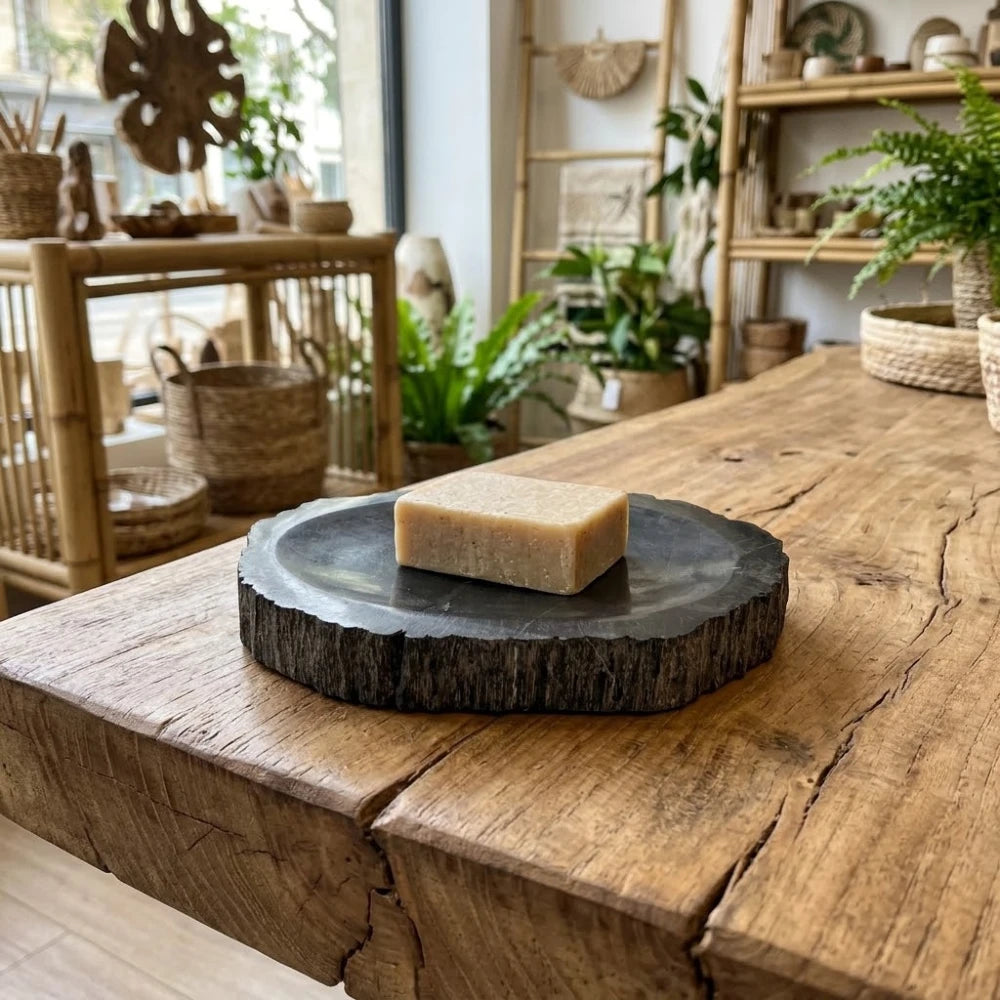 Porte-savon en bois fossilisé noir avec savon, posé sur une table en bois, pierre veinée aux bords bruts