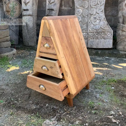 Commode triangulaire en bois recyclé à trois tiroirs ouverts présentée en extérieur