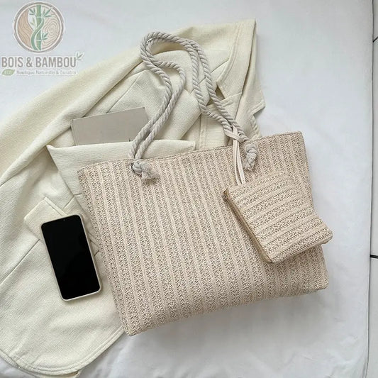 Cabas en paille tressée et pochette posés sur un vêtement beige, Bois Et Bambou Eco