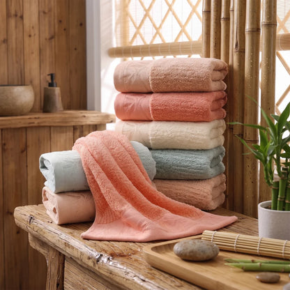 Serviettes de visage en bambou unies, plusieurs coloris, empilées dans une salle de bain en bois et bambou