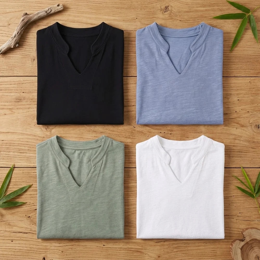 T-shirts col V femme en coton et fibre de bambou pliés sur une table en bois brut, quatre coloris noir bleu vert et blanc