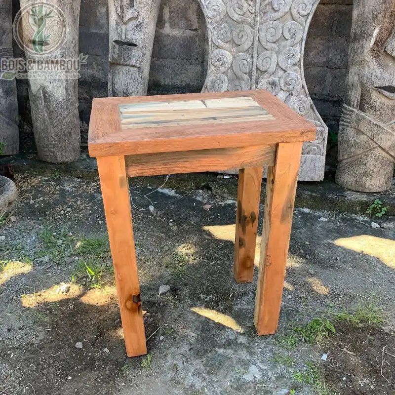 Table haute en bois recyclé à plateau multicolore présentée en extérieur
