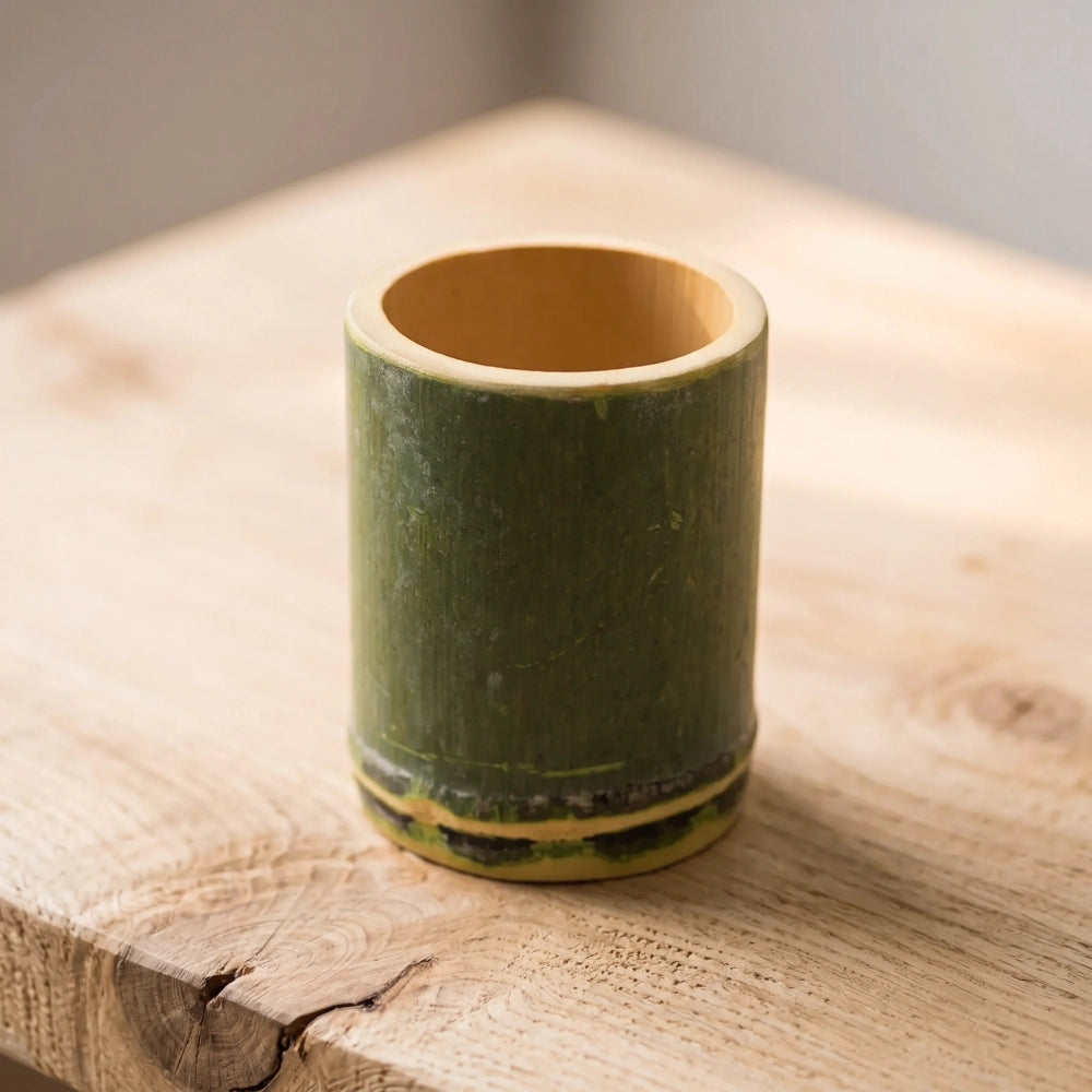 Tasse en bambou naturel ronde posée sur une table en bois clair, bambou vert avec base foncée