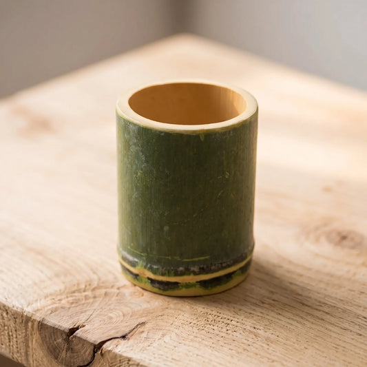 Tasse en bambou naturel ronde posée sur une table en bois clair, bambou vert avec base foncée