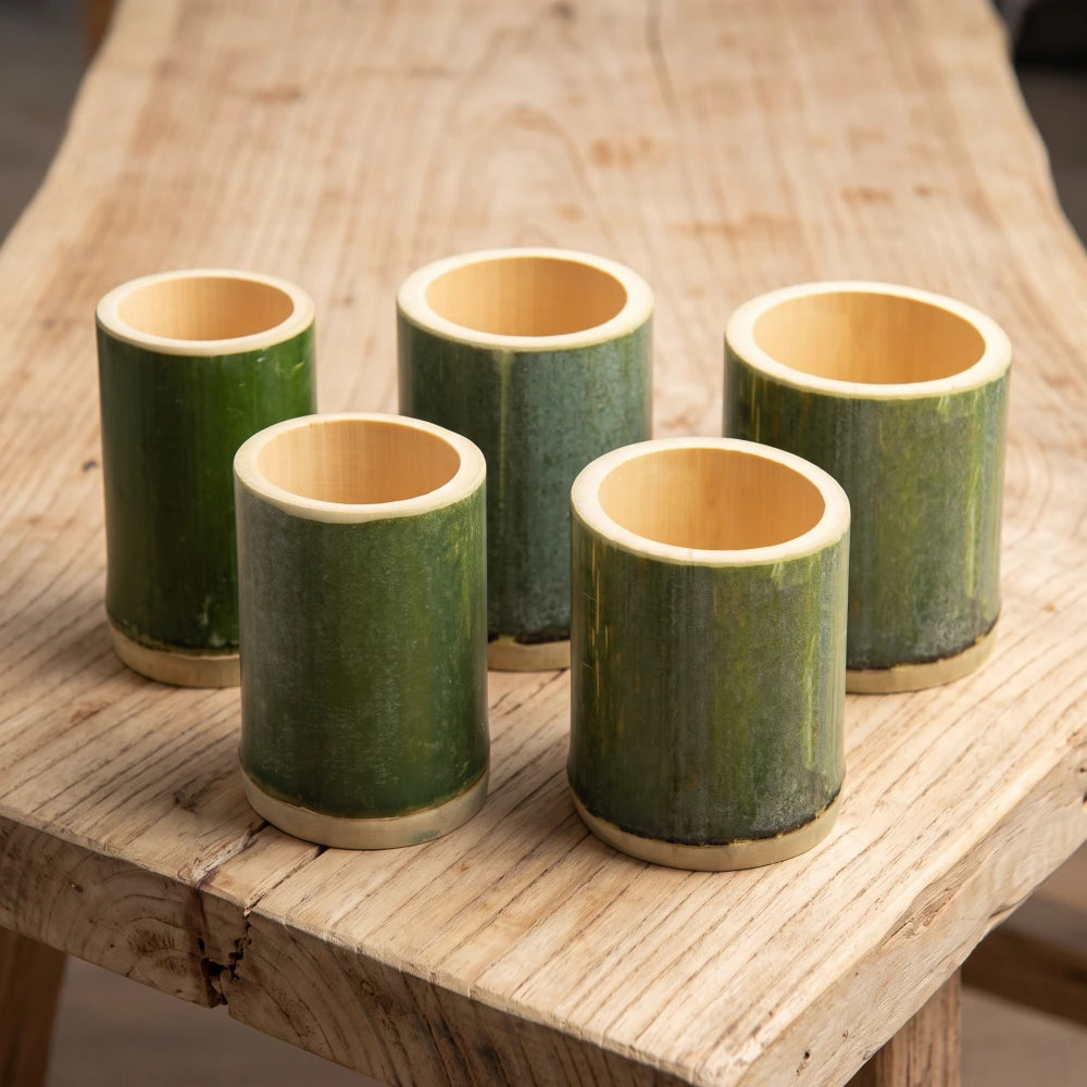 Tasses en bambou tube vert naturel de tailles différentes posées sur une table en bois