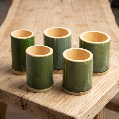 Tasses en bambou tube vert naturel de tailles différentes posées sur une table en bois