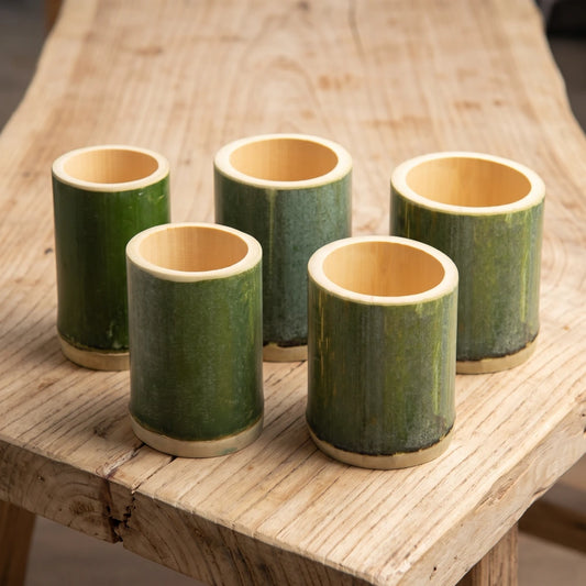 Tasses en bambou tube vert naturel de tailles différentes posées sur une table en bois