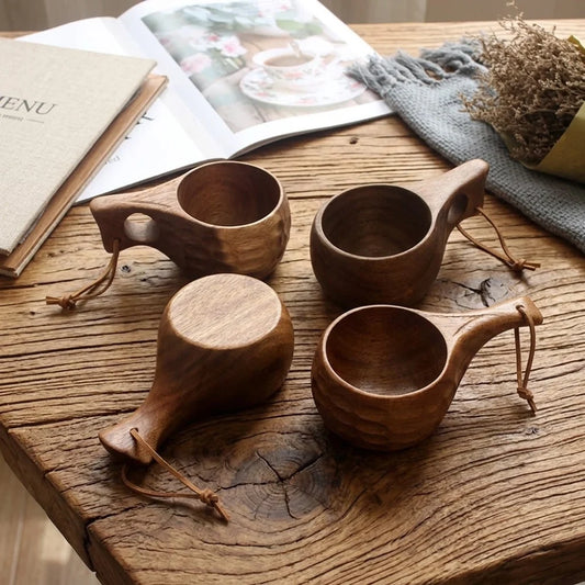 Lot de tasses en bois d'acacia style kuksa, 5 modèles d'anse différents, sur une table en bois