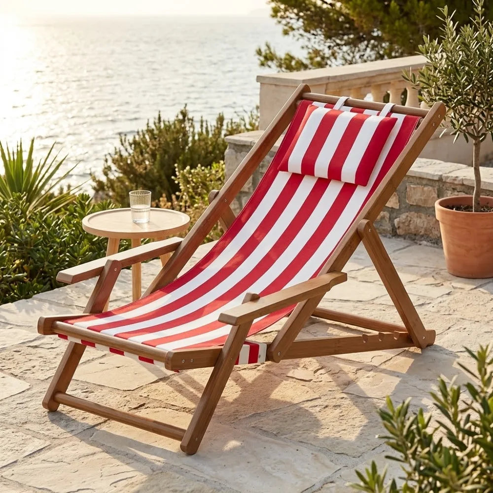 Transat en toile et bambou à accoudoirs, cadre brun et toile rayée rouge et blanc, sur une terrasse au bord de la mer
