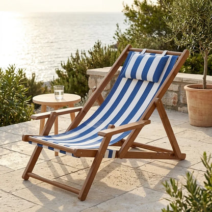 Transat en toile et bambou à accoudoirs, cadre brun et toile rayée bleu et blanc, sur une terrasse face à la mer