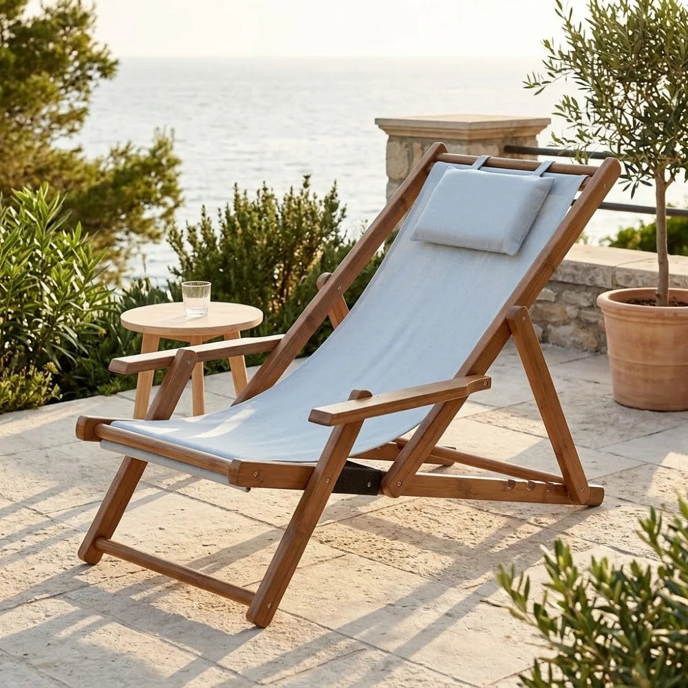 Transat en toile et bambou à accoudoirs, cadre brun et toile gris bleu clair, sur une terrasse méditerranéenne