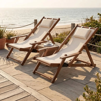 Transat en toile et bambou à accoudoirs, deux transats cadre brun et toile écrue sur une terrasse face à la plage